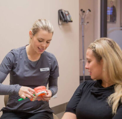 Dental hygienist explaining proper brushing technique to patient at Harmony Dental Care